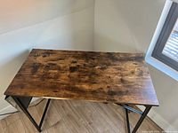 Top-down view of the desk showing the rustic brown wood surface with distressing and the black metal frame underneath.