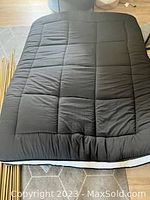 Black padded Japanese floor mattress futon shown laid flat with visible quilting and padding.