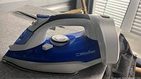Blue and white Mueller professional grade steam iron, side view showing ergonomic design, buttons and dial