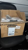Opened cardboard box labeled Stalwart showing safe contents including keypad safe, keys, and manuals inside.
