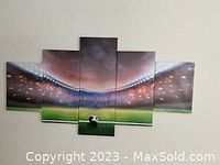 Five-panel canvas wall art showing soccer stadium interior with a green soccer ball on the grass, illuminated stands, and cloudy sky above.