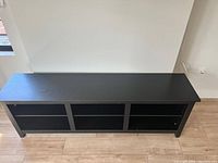 Front view of black Walker Edison TV stand with six cubby compartments, empty.