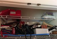 Shelves of assorted handbags and clutches arranged in a row, including red, black, and beige colors