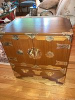 Front view showing two-door cabinet with brass decorative hardware and a bottom drawer