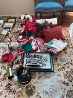 Overview of Christmas-themed pillows, placemats, trays, mugs, nutcrackers, and ornaments arrayed on a carpet.