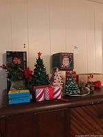 Photo showing ceramic Christmas trees, wrapped decorations and vintage holiday items on tabletop