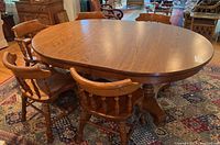 Oval wooden dining table with six matching chairs arranged around it on a patterned rug