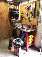 Overview of workbench area showing power tool boxes, toolbox, assorted hand tools on pegboard and shelves.