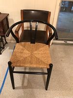 Photo of black wooden frame chair with woven seat, showing the top view and front legs.