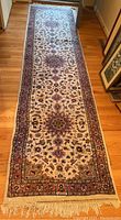 Full view of the runner with medallion and floral design showing the intricate pattern and fringed ends on hardwood floor.