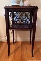 Front view of wooden side table showing the geometric cutout panel design and four legs.