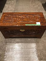 Full front view of the wooden storage box showing overall size, carvings, and lock.