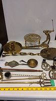 Full collection showing various brass decor including candle holders, a golfer figurine, trivets, serving utensils and horse-themed pieces.