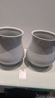 Pair of white ceramic pots side by side, showing shape and size relative to each other.