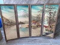 Full view of embroidered four-panel screen showing mountain and landscape embroidery in blue, brown, and green tones.