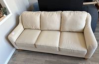 Front left view of beige La-Z-Boy sofa showing overall shape, arms and cushions