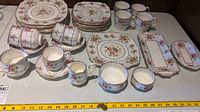 Full set arranged showing stacks of square dinner plates, round side plates, teacups, saucers, mugs, sauce bowls, serving dishes and cream jug.