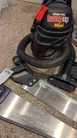 Shop Vac Hang Up Mini with flexible hose and two hand saws lying on carpeted floor