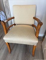 Front view of wood side chair with beige diamond-patterned upholstery and curved wood arms.