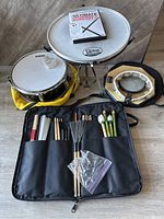 Full overview of the lot showing snare drum, stand, tambourine, drum stick kit with various sticks/mallets, and workout DVD.