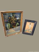 Photo of two framed portraits side by side: Napoleon in black frame, Admiral Nelson in gold-toned ornate frame