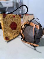 Side-by-side view of the two bags, showing brocade tote and dark brown designer-style backpack