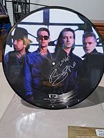 Full image of the 12-inch picture disc vinyl featuring U2 band members and Bono's signature in silver marker.
