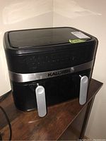 Front view of Kalorik air fryer showing brand name and dual silver handles on basket compartments.
