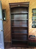 Front view of tall wood laminate bookshelf with five shelves, showing the wood trim and overall design.