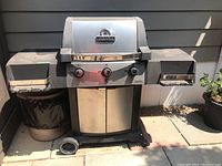 Front view of Broil King propane BBQ grill with stainless steel hood, side shelves, and wheels.