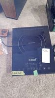 Photo of a black Master Chef single-burner induction cooktop with digital controls and induction cooking circle markings, placed on carpeted floor with visible power cord.