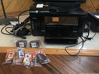 Front view of the HP OfficeJet 6500A Plus Wireless printer with ink cartridges laid out in front.