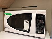 Front view of the Danby microwave showing the keypad and window on door with measurement sticker 17.5x11.5x10 inches.