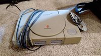 Sony PlayStation SCPH-7501 console without controllers, beige color with cables visible.