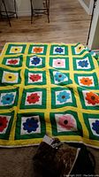Full view of colorful floral patchwork quilt laid flat on floor with visible pattern of flowers and geometric borders.