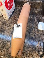 Wooden rolling pin on kitchen counter with label attached, showing condition and shape of the rolling pin