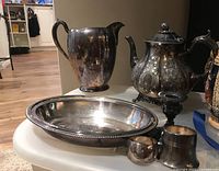 Front view showing the collection: teapot, pitcher, serving dish, candlestick, napkin ring, and small container.