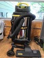 Full view of Stanley wet/dry vacuum with attached hose and included attachments (brush, floor nozzle).