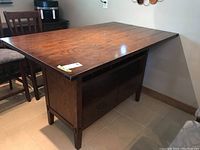 Side view showing wood high top table with drawers and cubbies, and brown wood finish