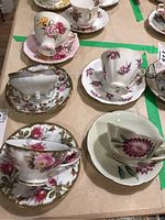 Top view of five tea cups and saucers, showing varied floral designs and gold trims