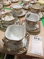 Assorted tea cups and saucers showing detailed floral and gold designs.