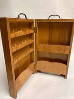 Open view of the wooden sewing organizer showing three rows of pegs for thread spools and internal storage compartments.