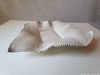 White ceramic platter with wavy edges, floral embossed detail and glossy finish.