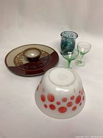Overview of all items including decorative plate with bowl, multicolor glass tumbler, two green-stemmed glasses, and white mixing bowl with red polka dots