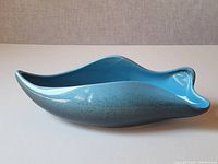 Side view of blue teal ceramic Beauceware console dish, showing curved organic shape and glossy finish.