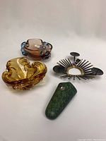 Lot overview photo showing all four items: two glass pieces, metal candle holder, and green stone piece