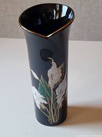 Front view of the black ceramic vase showing the floral pattern and gold trim on the rim