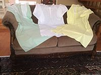 Three vintage nightgowns displayed on a sofa; colors are light green, white, and yellow, showing overall front view and shape.