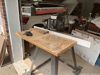 Full view of the Craftsman 10 inch electronic radial arm saw on wooden tabletop with rolling metal stand, placed in garage.