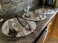 Wide angle showing multiple jewelry items arranged on woven placemats including necklaces, earrings, rings, and pins